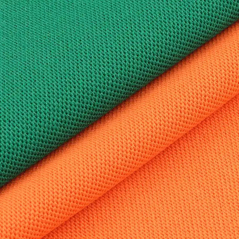 Gros plan sur deux tissus piqués respirants de Longan Craft France, l'un vert et l'autre orange, superposés en diagonale pour montrer le motif œil d'oiseau - un tissu idéal pour les polos et les T-shirts d'été.