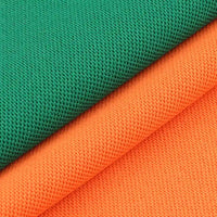 Gros plan sur deux tissus piqués respirants de Longan Craft France, l'un vert et l'autre orange, superposés en diagonale pour montrer le motif œil d'oiseau - un tissu idéal pour les polos et les T-shirts d'été.