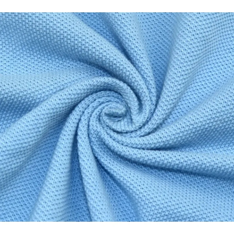 Gros plan sur le tissu piqué bleu clair de Longan Craft France, motif œil d'oiseau à fil simple, disposé en spirale pour mettre en valeur sa maille respirante, parfaite pour les polos DIY et les T-shirts d'été.