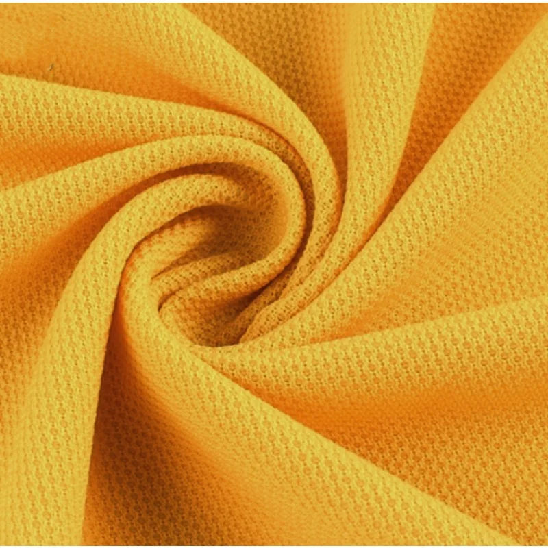 Gros plan sur le Tissu piqué motif œil d'oiseau à fil simple Longan Craft France, torsadé pour montrer son tissage doux et flexible. Ce tricot d'été respirant est idéal pour les polos et les T-shirts DIY.