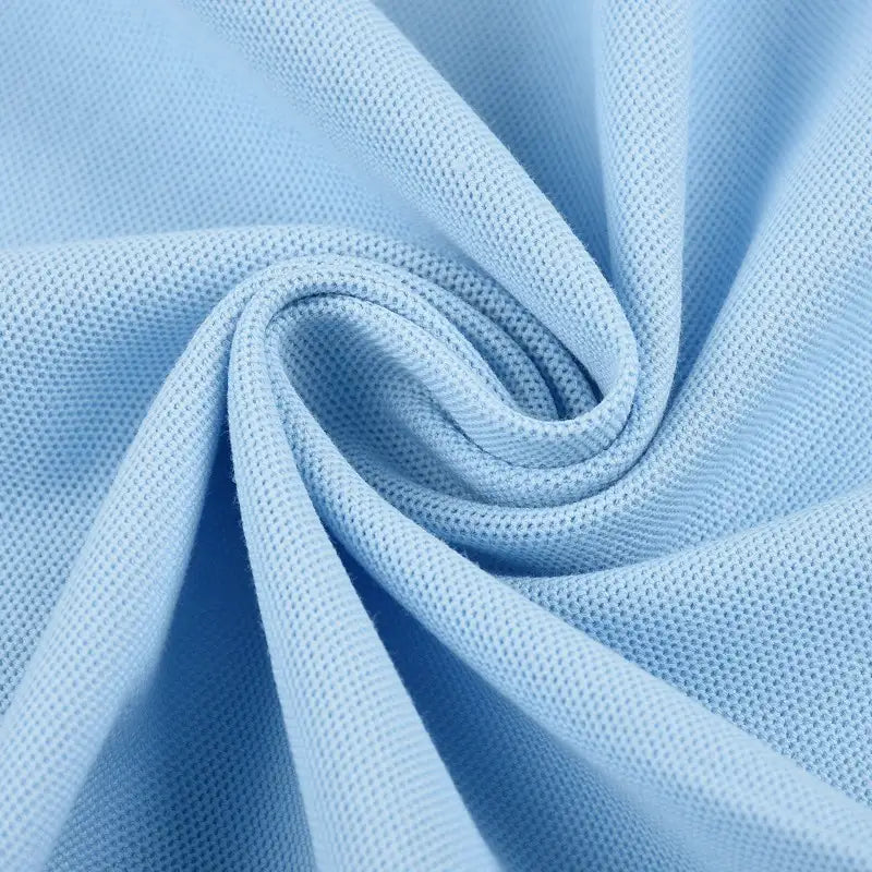 Gros plan sur le tissu piqué bleu clair motif œil d'oiseau à fil simple de Longan Craft France, disposé en tourbillon pour mettre en valeur sa maille respirante et son tissage texturé - idéal pour les polos et les T-shirts DIY de l'été.