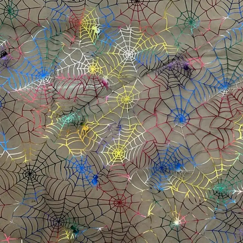 La toile d'araignée au mètre en organza coloré et extensible de Longan Craft France décore un fond neutre avec des toiles d'araignée d'Halloween qui se chevauchent. Des araignées en plastique assorties complètent ce look festif et créatif pour les costumes ou les travaux manuels.