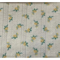 Gros plan sur le tissu pointelle à petites fleurs au mètre de Longan Craft France, un tricot imprimé d'été avec des rangées de petits motifs floraux jaunes et verts et des détails verticaux en forme de dentelle, idéal pour les robes et les gilets d'enfants.