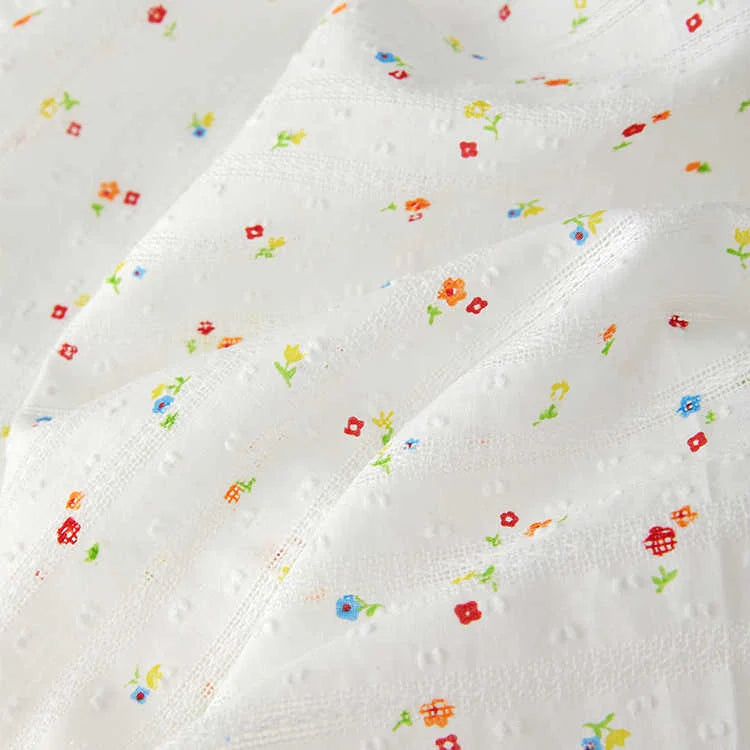 Tissu plumetis à petites fleurs au mètre de Longan Craft France : coton léger, confortable, à texture discrète et jolies fleurs colorées, idéal pour la confection de vêtements.