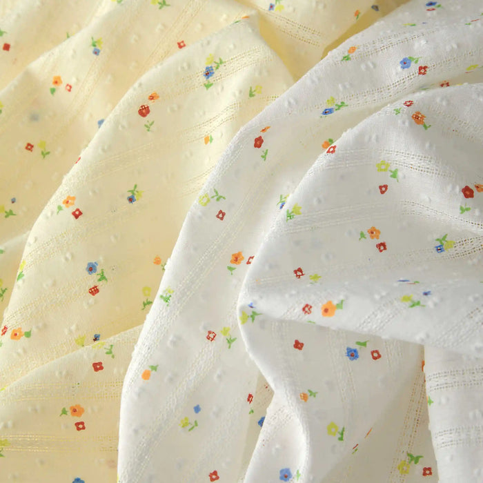 Gros plan sur le Tissu plumetis à petites fleurs au mètre de Longan Craft France - un tissu de coton confortable avec des points subtils et des imprimés floraux, parfait pour l'habillement.
