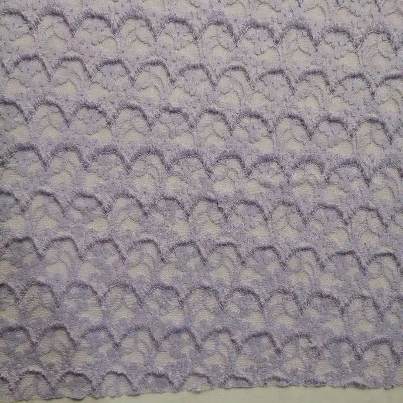 Un gros plan de la Dentelle extensible au mètre de Longan Craft France montre son tissu violet clair à motifs de coquilles Saint-Jacques avec des zones texturées, surélevées et plates pour un aspect 3D unique, parfait pour les robes et la lingerie DIY.