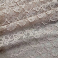 Un gros plan de la dentelle extensible au mètre de Longan Craft France révèle la broderie florale frangée complexe et les textures délicates - un tissu de dentelle DIY idéal pour les peignoirs et la lingerie.