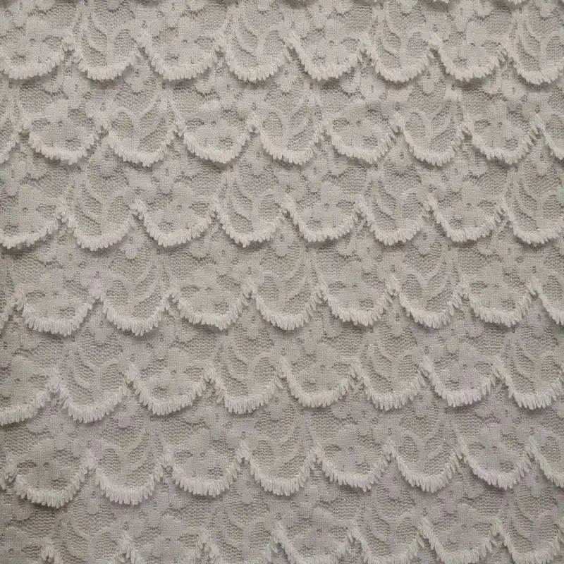 Gros plan sur la dentelle extensible au mètre de Longan Craft France, qui présente une dentelle brodée de fleurs complexes avec des franges, parfaite pour les projets de peignoirs et de lingerie.