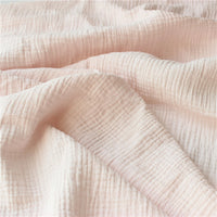 Découvrez le tissu double gaze doux au mètre de Longan Craft France : léger, rose clair et texturé façon quadrillage, parfait pour coudre des vêtements bébé tout en douceur.