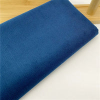 Gros plan sur Tissu velours côtelé uni 21 côtes au mètre de Longan Craft France : velours côtelé bleu doux à fines côtes, soigneusement plié sur du blanc-idéal pour pantalons et vêtements confortables.