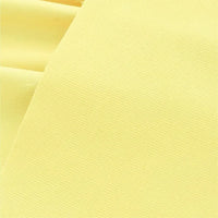 Un gros plan du tissu velours côtelé uni 21 côtes au mètre de Longan Craft France montre un coton doux, jaune clair avec de fines côtes, idéal pour les pantalons. Les délicates lignes horizontales du tissu et sa texture veloutée sont clairement visibles.