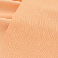 Un gros plan du Tissu velours côtelé uni 21 côtes au mètre de Longan Craft France montre sa couleur pêche claire, sa texture fine en coton côtelé et sa surface lisse. Le confortable velours côtelé est légèrement plié dans le coin supérieur gauche.