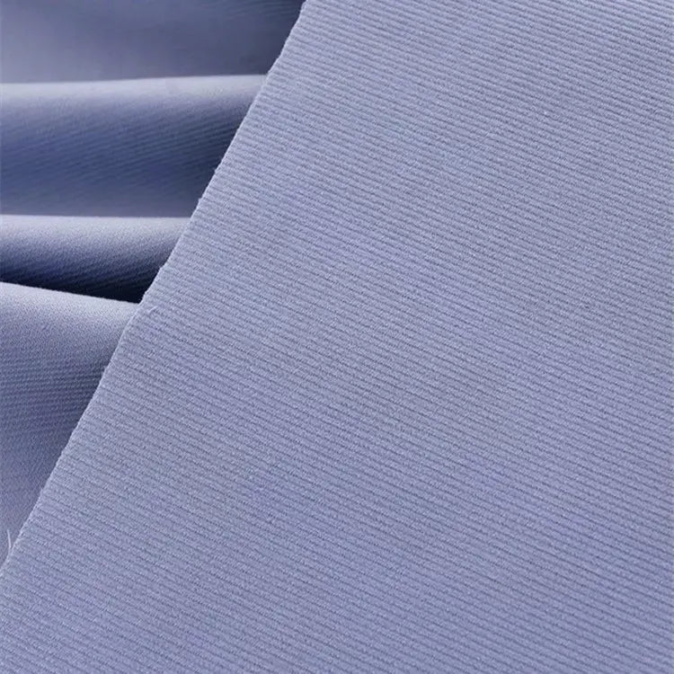 Gros plan sur le Tissu velours côtelé uni 21 côtes au mètre de Longan Craft France en bleu clair : fines nervures verticales en coton, texture douce, superposition soignée - idéal pour les vêtements et pantalons confortables.