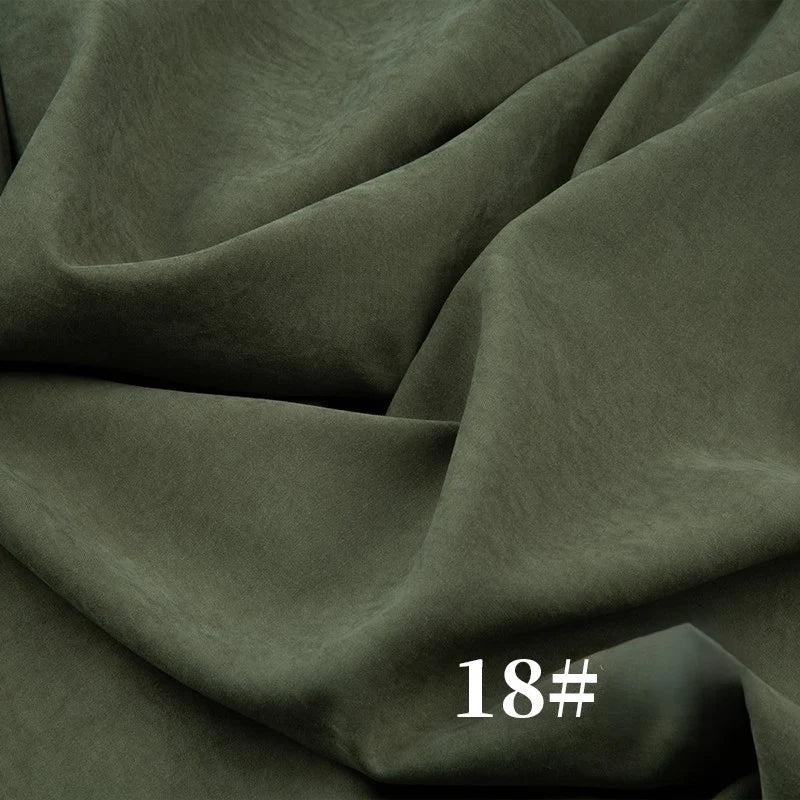 Un gros plan du microsuède polyester peau de pêche uni mi-épais au mètre de Longan Craft France montre sa texture brossée douce et veloutée en vert olive foncé, drapée librement avec des plis visibles. Le chiffre "18#" apparaît en blanc en bas à droite.
