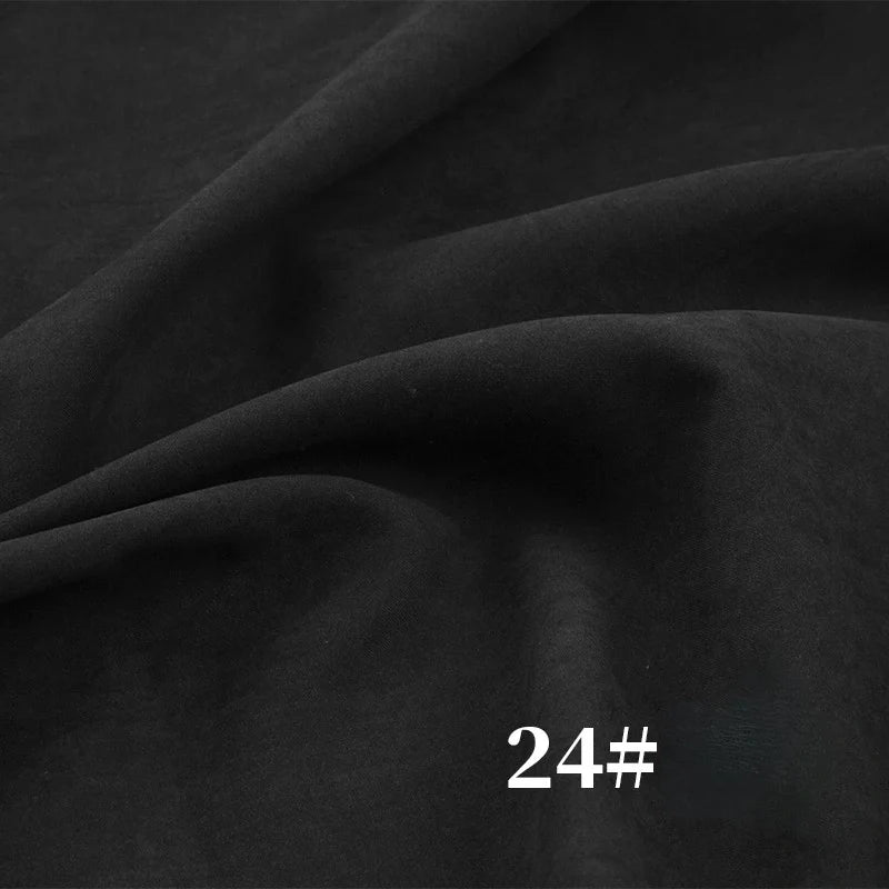 Gros plan sur le tissu noir "Microsuède polyester peau de pêche uni mi-épais au mètre" de Longan Craft France, un tissu brossé à la texture veloutée et aux plis visibles ; la mention blanche "24#" apparaît dans le coin inférieur droit.