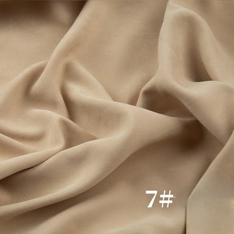 Un tissu peau de pêche beige clair Longan Craft France en microsuède polyester mi-épais, à texture veloutée et douce. Pliures visibles. Le numéro "7#" est imprimé en blanc en bas à droite. Idéal pour robes et projets couture.