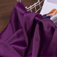 Le tissu satin charmeuse uni au mètre de Longan Craft France, en violet lisse, sublime vos créations de robes de mariée et soirée. Satin crêpe épais présenté avec panier blanc et magazine mode-idéal pour toutes vos envies couture.