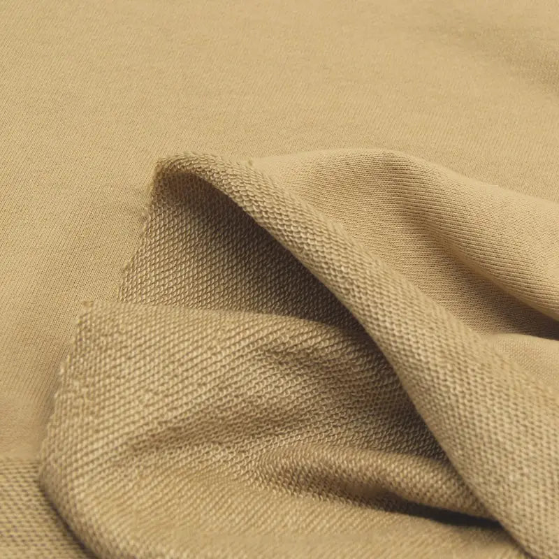 Gros plan sur le Tissu French Terry en coton uni au mètre de Longan Craft France, montrant sa couleur beige, son recto lisse et son verso texturé - un tissu épais idéal pour les sweatshirts et les sweats à capuche.
