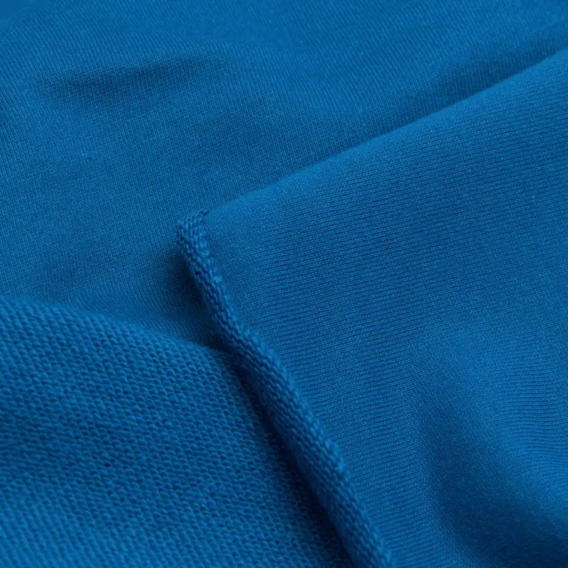 Gros plan sur un tissu bleu avec deux textures et une couture visible - idéal pour les projets de sweat-shirts utilisant le Tissu French Terry en coton uni au mètre de Longan Craft France, un tissu épais parfait pour sweat-shirts à capuche.
