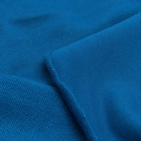 Gros plan sur un tissu bleu avec deux textures et une couture visible - idéal pour les projets de sweat-shirts utilisant le Tissu French Terry en coton uni au mètre de Longan Craft France, un tissu épais parfait pour sweat-shirts à capuche.