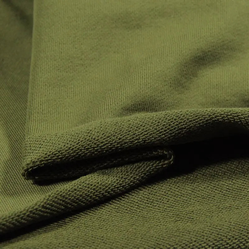 Gros plan sur le Tissu French Terry en coton uni au mètre de Longan Craft France en vert olive, montrant son tissage texturé et sa surface douce. Le tissu épais est plié pour présenter le recto et le verso - idéal pour les sweat-shirts à capuche.