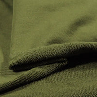 Gros plan sur le Tissu French Terry en coton uni au mètre de Longan Craft France en vert olive, montrant son tissage texturé et sa surface douce. Le tissu épais est plié pour présenter le recto et le verso - idéal pour les sweat-shirts à capuche.