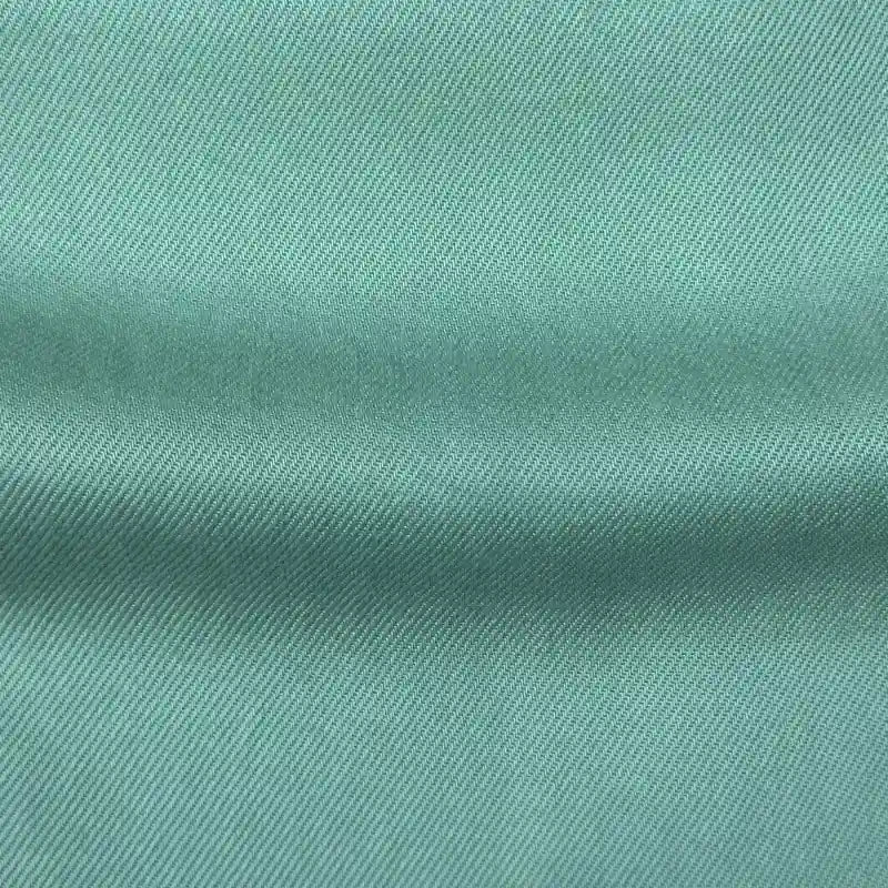 Gros plan sur Tissu en lyocell denim multicolore au mètre de Longan Craft France : denim lyocell durable vert clair avec un tissage diagonal subtil et un pli horizontal visible, parfait pour des jeans respirants et confortables.