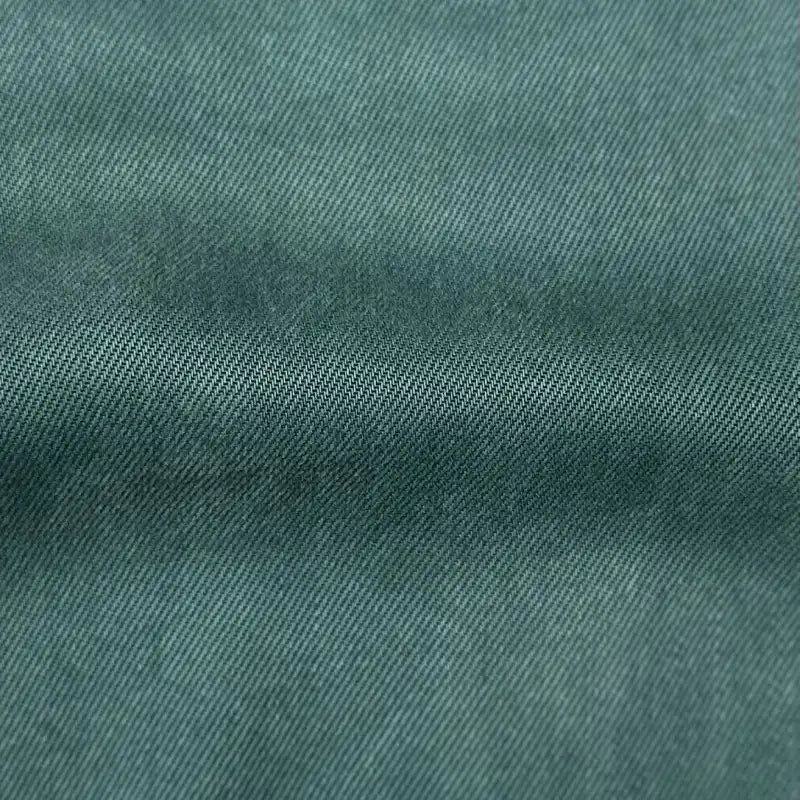 Gros plan sur le tissu en lyocell denim multicolore au mètre de Longan Craft France, montrant son tissage sergé diagonal visible et son léger pli horizontal - un textile idéal respirant et confortable pour les jeans.