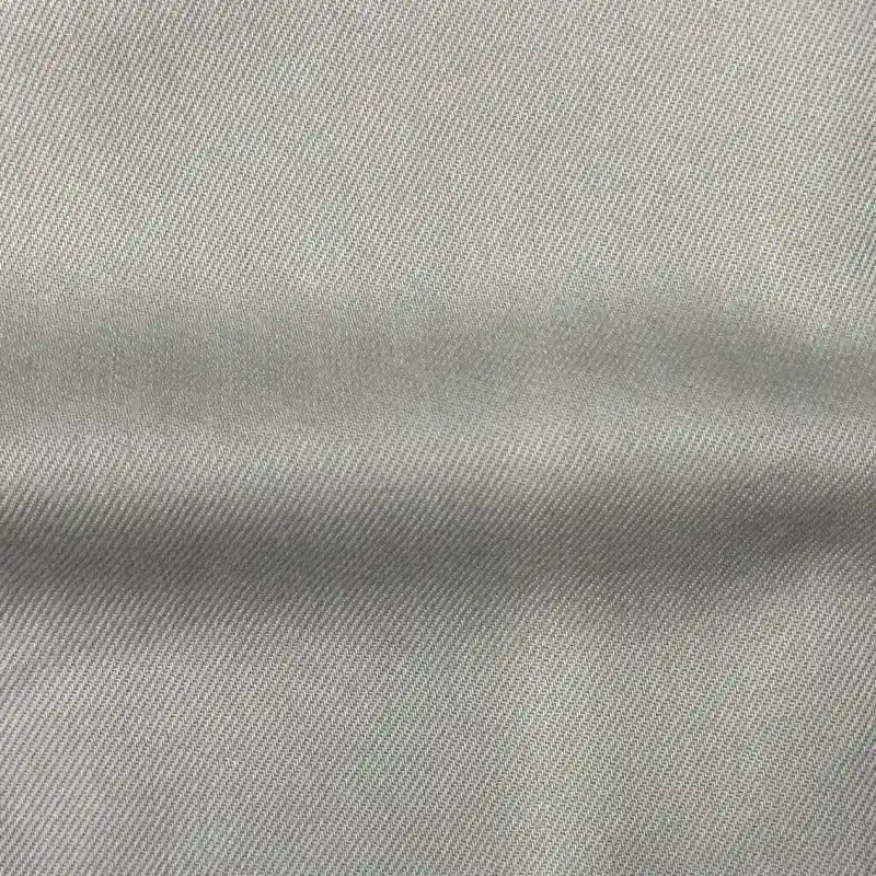 Un gros plan du tissu en lyocell denim multicolore au mètre de Longan Craft France montre son tissage sergé gris clair et son pli, mettant en valeur ce textile respirant et confortable, idéal pour les jeans.