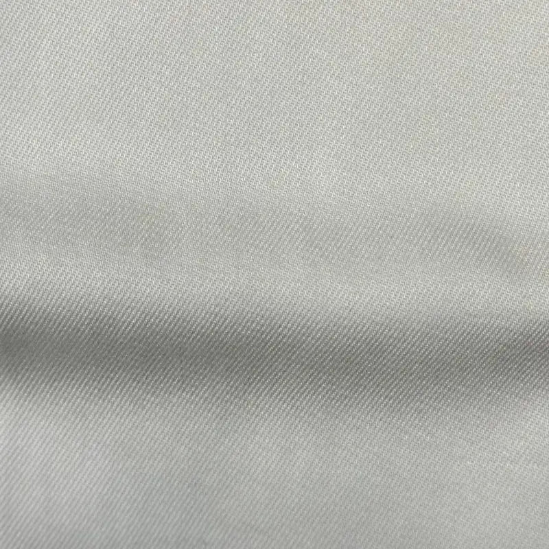 Gros plan sur Tissu en lyocell denim multicolore au mètre de Longan Craft France, un textile sergé durable, blanc cassé, avec un tissage diagonal subtil et des plis horizontaux - un lyocell respirant et confortable, idéal pour les jeans.