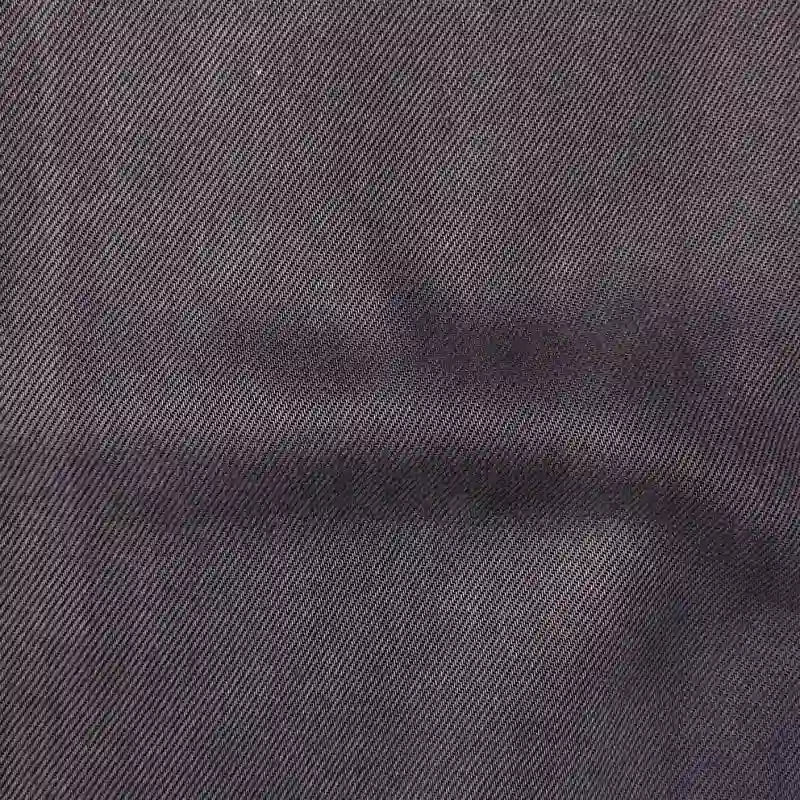 Gros plan sur le Tissu en lyocell denim multicolore au mètre de Longan Craft France, un tissu lyocell sergé gris foncé avec une subtile trame diagonale et une légère marque horizontale - respirant, confortable et parfait pour les jeans.