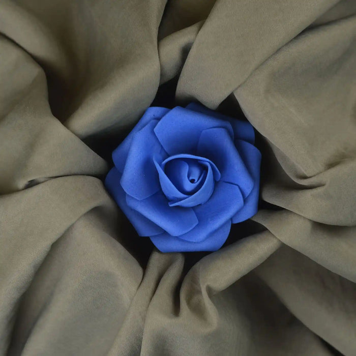 Une rose bleue trône au centre du tissu froissé Tissu peau de pêche uni double face de Longan Craft France. Les plis souples du tissu polyester microfibre marron clair rayonnent vers l'extérieur dans une présentation en forme de fleur.