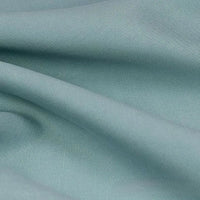 Un gros plan sur le tissu lyocell et lin uni au mètre de Longan Craft France révèle des plis doux, une surface lisse et subtilement texturée, et un tissage fin - un textile infroissable et durable, idéal pour les robes de chambre et les vêtements.