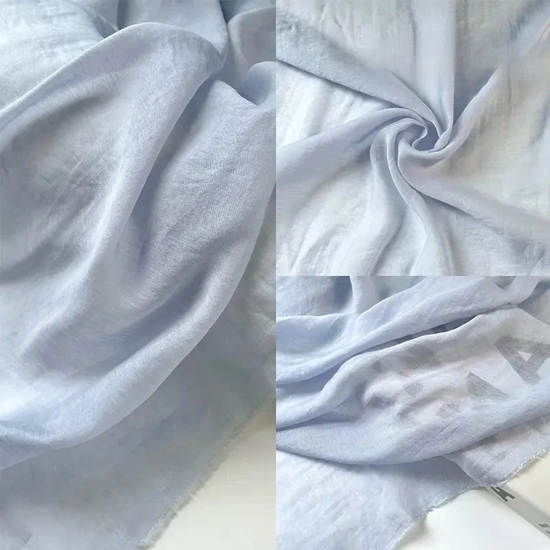 Le Tissu lin et soie uni au mètre de Longan Craft France, un fin mélange de lin, de lyocell et de soie pour l'ameublement, est présenté dans des vues rapprochées qui mettent en évidence sa texture lisse, ses plis doux et ses lettres imprimées subtiles sur le bord du tissu.