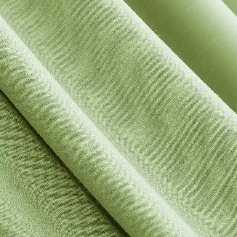Gros plan sur le Jersey modal uni au mètre de Longan Craft France, montrant le tissu coton-modal lisse et finement tissé en vert clair, un textile respirant idéal pour les vêtements de nuit, avec des plis souples et un drapé doux.