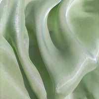 Gros plan sur le "Tissu organza uni au mètre" vert clair et chatoyant de Longan Craft France, léger et transparent, avec des plis doux - un choix parfait pour les vêtements et la décoration.