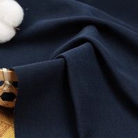 Un morceau de tissu piqué uni au mètre bleu foncé de Longan Craft France est présenté à côté d'un panier en osier et d'une balle de coton blanc, parfaits pour bricoler des chemises et des polos d'été.