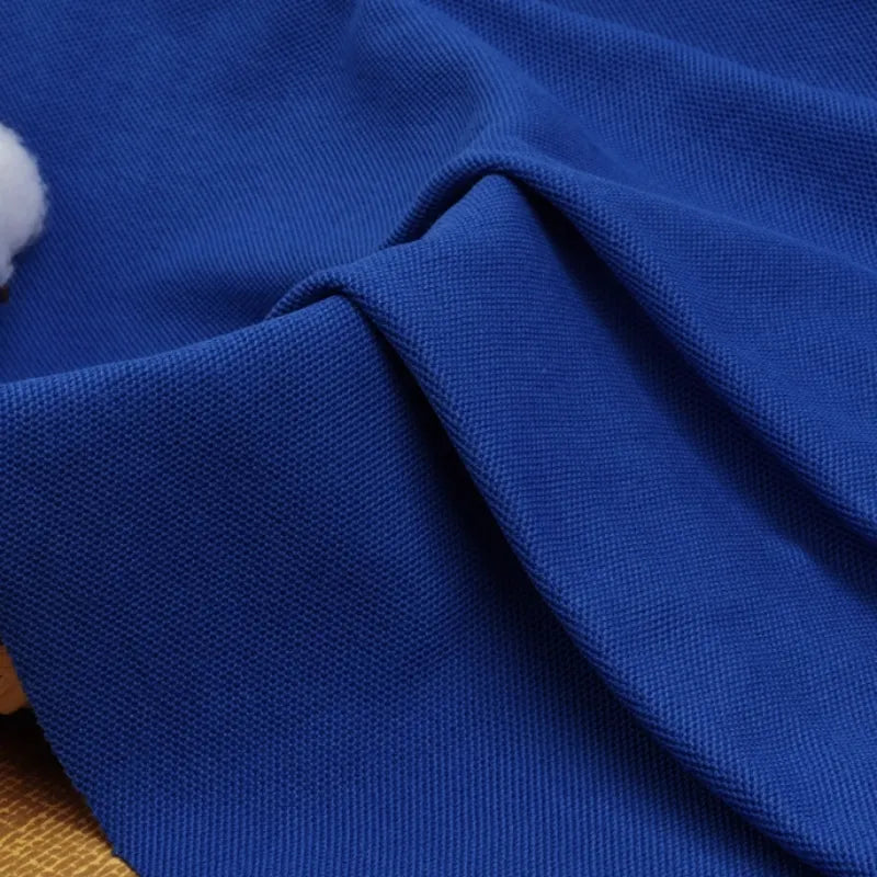 Gros plan sur le Tissu piqué uni au mètre de Longan Craft France, un tissu bleu en coton-polyester à armure apparente, idéal pour les chemises DIY ou les polos d'été à manches courtes.