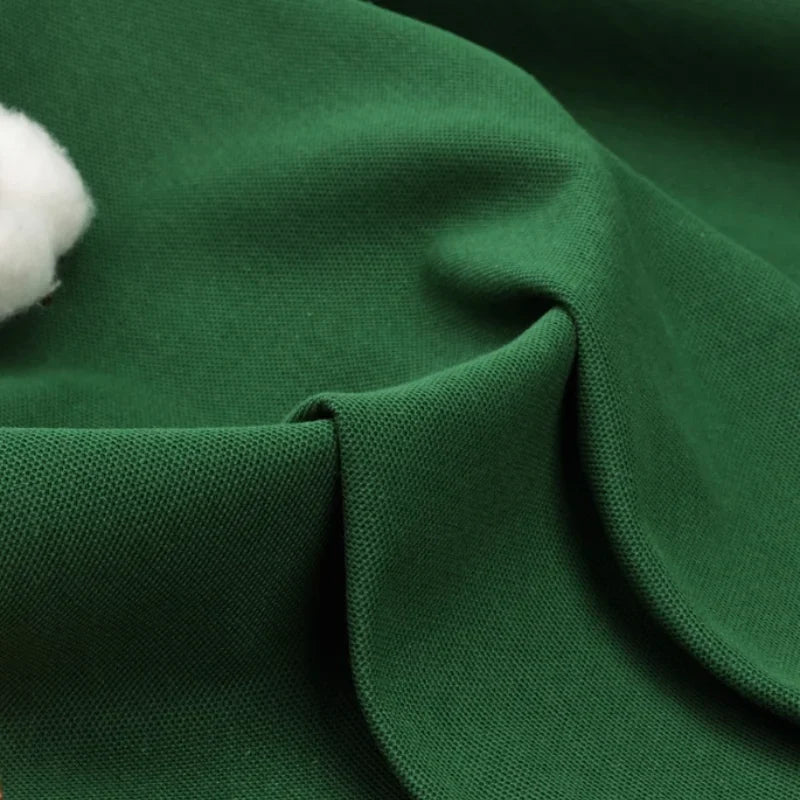 Un gros plan sur le tissu piqué uni au mètre de Longan Craft France montre sa texture douce et lisse en coton-polyester et son tissage visible - idéal pour les polos et les chemises d'été DIY, avec une touche de coton blanc qui met en valeur ce tissu classique.