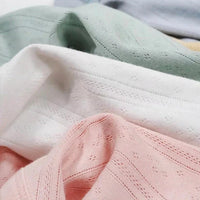 Gros plan sur la maille pointelle côtelée unie au mètre de Longan Craft France, un tissu en coton biologique doux et respirant, de couleur vert pastel, blanc et rose, idéal pour les vêtements de bébé grâce à sa texture délicatement côtelée et ses minuscules perforations.