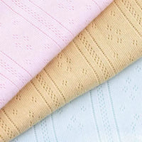Trois pièces de Longan Craft France maille pointelle côtelée unie au mètre en rose pastel, beige et bleu clair présentent un délicat motif d'œillets, idéal pour des vêtements de bébé doux et respirants en coton biologique.