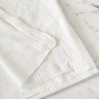 Gros plan sur Maille pointelle côtelée unie au mètre de Longan Craft France, un tissu pointelle en coton biologique doux et respirant, idéal pour vêtements bébé, avec motif subtil de rayures et losanges sur fond blanc marbré.