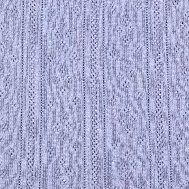 Gros plan sur Maille pointelle côtelée unie au mètre de Longan Craft France, un tissu de coton biologique violet clair avec des rayures verticales en dentelle et un ajourage en forme de losange, idéal pour les vêtements de bébé et d'enfant doux et perméables à l'air.