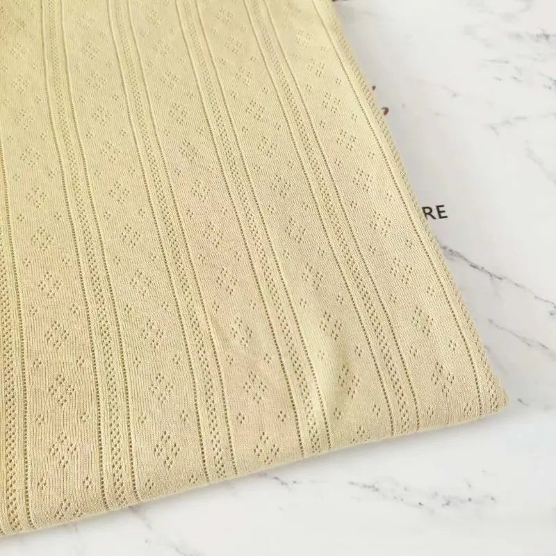 Gros plan sur la Maille pointelle côtelée unie au mètre de Longan Craft France : une maille douce et respirante en coton biologique pour les vêtements de bébé, présentée à plat sur un marbre blanc - parfaite pour les projets de couture de tissus bébé et de sous-vêtements pour enfants.