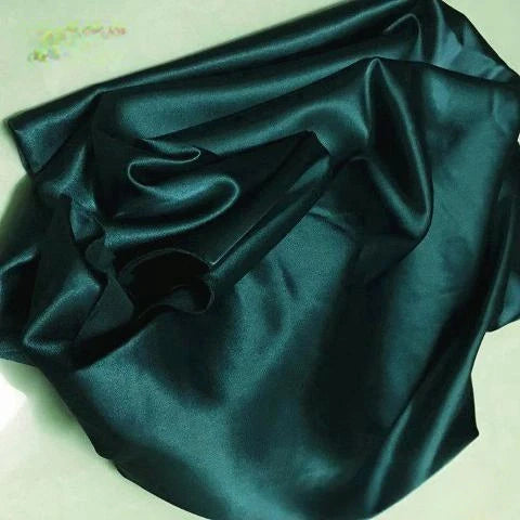 Le Tissu satin polyester uni au mètre de Longan Craft France, extensible et brillant en vert foncé, est idéal pour des vêtements élégants et confortables.