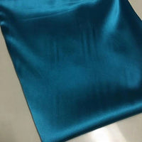 Le Tissu satin polyester uni au mètre de Longan Craft France, en bleu sarcelle avec une légère brillance et douceur, est idéal pour des vêtements ajustés et confortables.