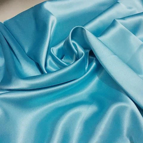 Gros plan sur un Tissu satin polyester uni au mètre de Longan Craft France, bleu clair et brillant, disposé en plis souples et en tourbillon central, reflétant la lumière pour mettre en valeur sa texture lisse et brillante - parfait pour des vêtements ajustés et confortables.