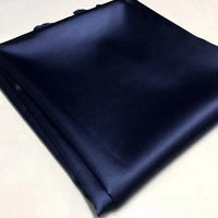 Un morceau de Tissu satin polyester uni au mètre de Longan Craft France, de couleur bleu marine foncé, est soigneusement plié sur une surface claire. Ce satin extensible est lisse, brillant et idéal pour créer des vêtements ajustés et confortables.