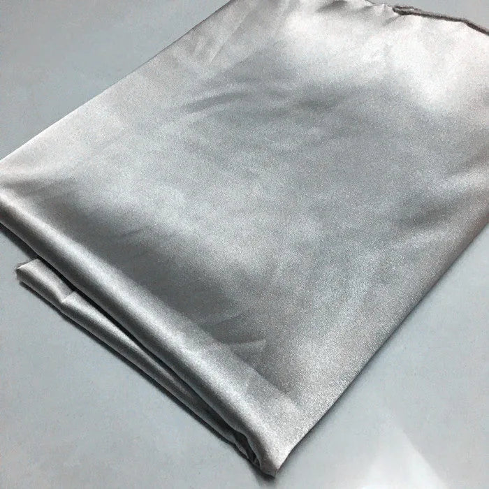 Un morceau plié de tissu polyester satiné brillant de Longan Craft France (Tissu satin polyester uni au mètre | Tissu satin extensible) repose sur une surface gris clair. Il semble lisse, réfléchissant et légèrement plissé, ce qui est idéal pour des vêtements ajustés et confortables.
