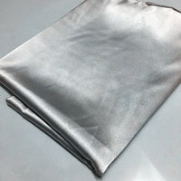Un morceau plié de tissu polyester satiné brillant de Longan Craft France (Tissu satin polyester uni au mètre | Tissu satin extensible) repose sur une surface gris clair. Il semble lisse, réfléchissant et légèrement plissé, ce qui est idéal pour des vêtements ajustés et confortables.